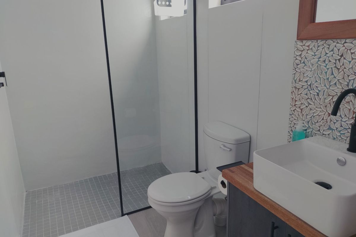 Modern bathroom featuring a walk-in shower with glass screen, vessel sink on a vanity cabinet, and decorative mosaic tile backsplash.
