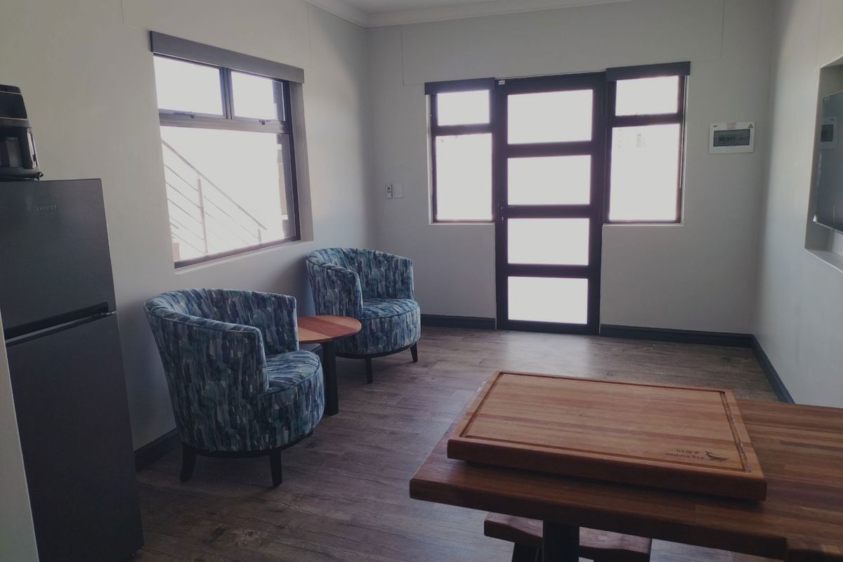 A bright living area featuring laminate flooring, aluminium window and door frames, and a built-in wall niche for media or display.