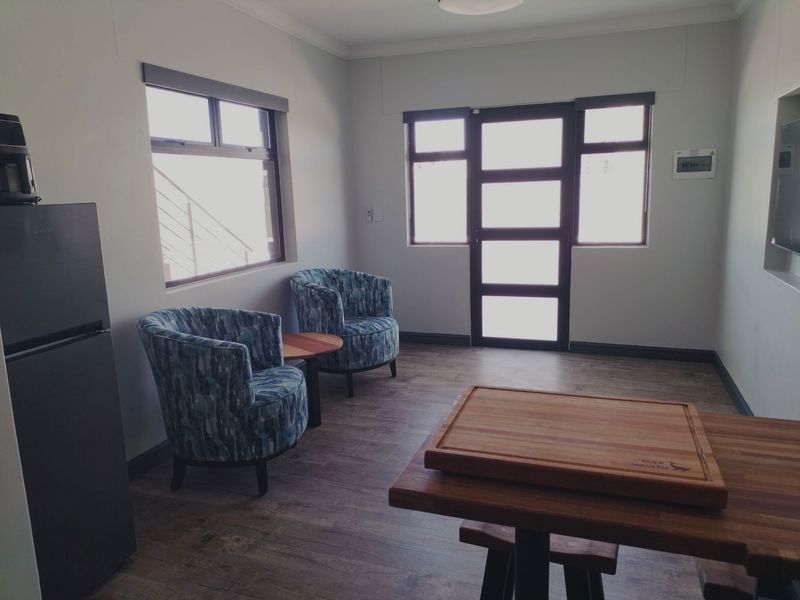 A bright living area featuring laminate flooring, aluminium window and door frames, and a built-in wall niche for media or display.
