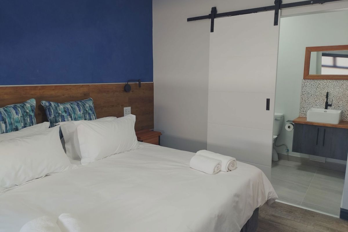 A well-maintained bedroom featuring a modern sliding barn door leading to an en-suite bathroom with a contemporary vanity and vessel sink.