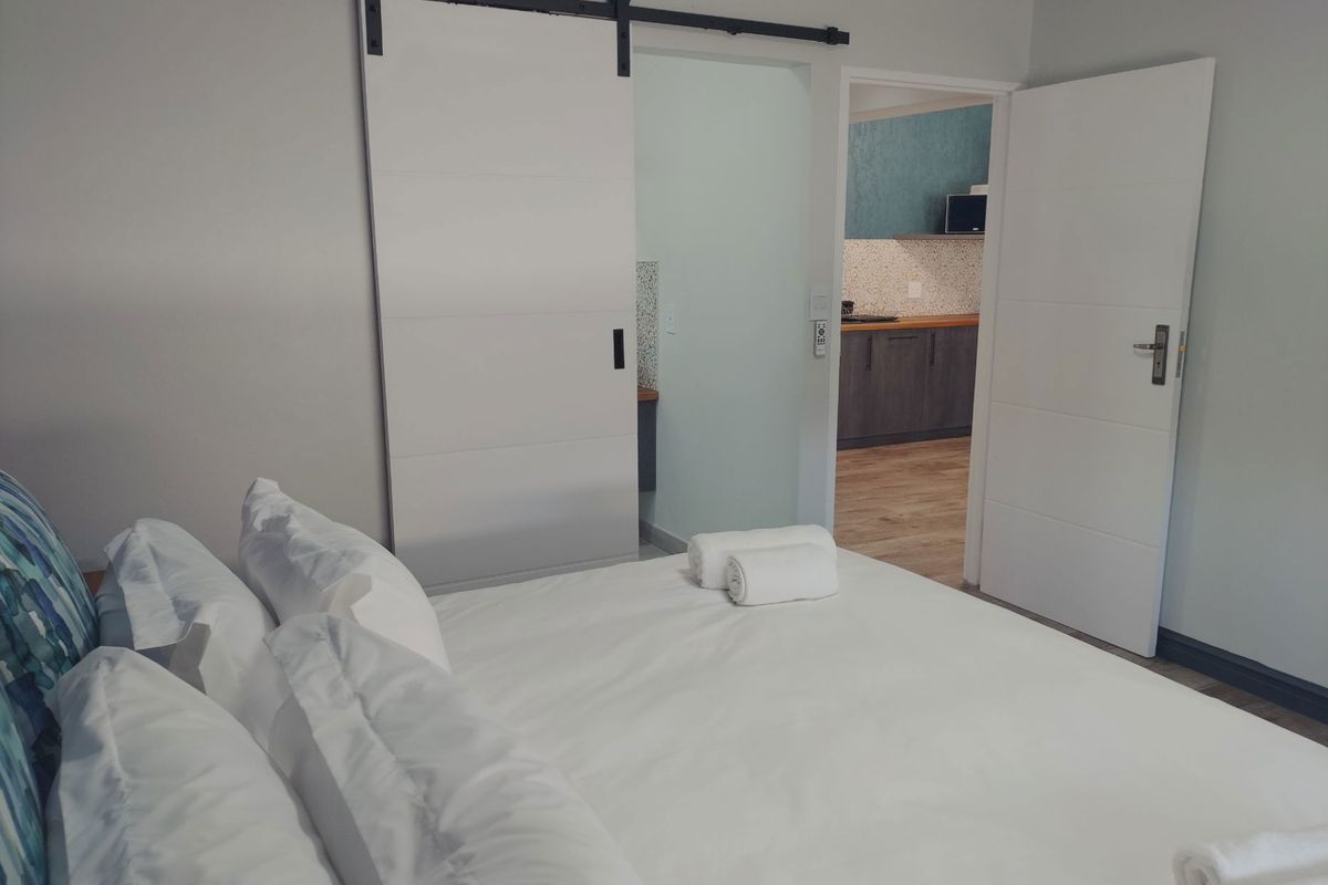 A well-maintained bedroom featuring a modern sliding barn door and a view into an adjacent kitchen area with contemporary cabinetry.