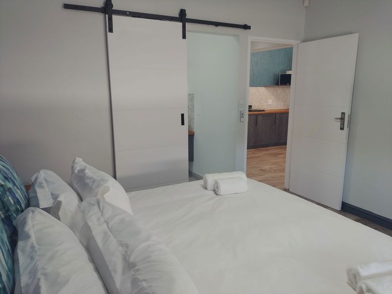 A well-maintained bedroom featuring a modern sliding barn door and a view into an adjacent kitchen area with contemporary cabinetry.