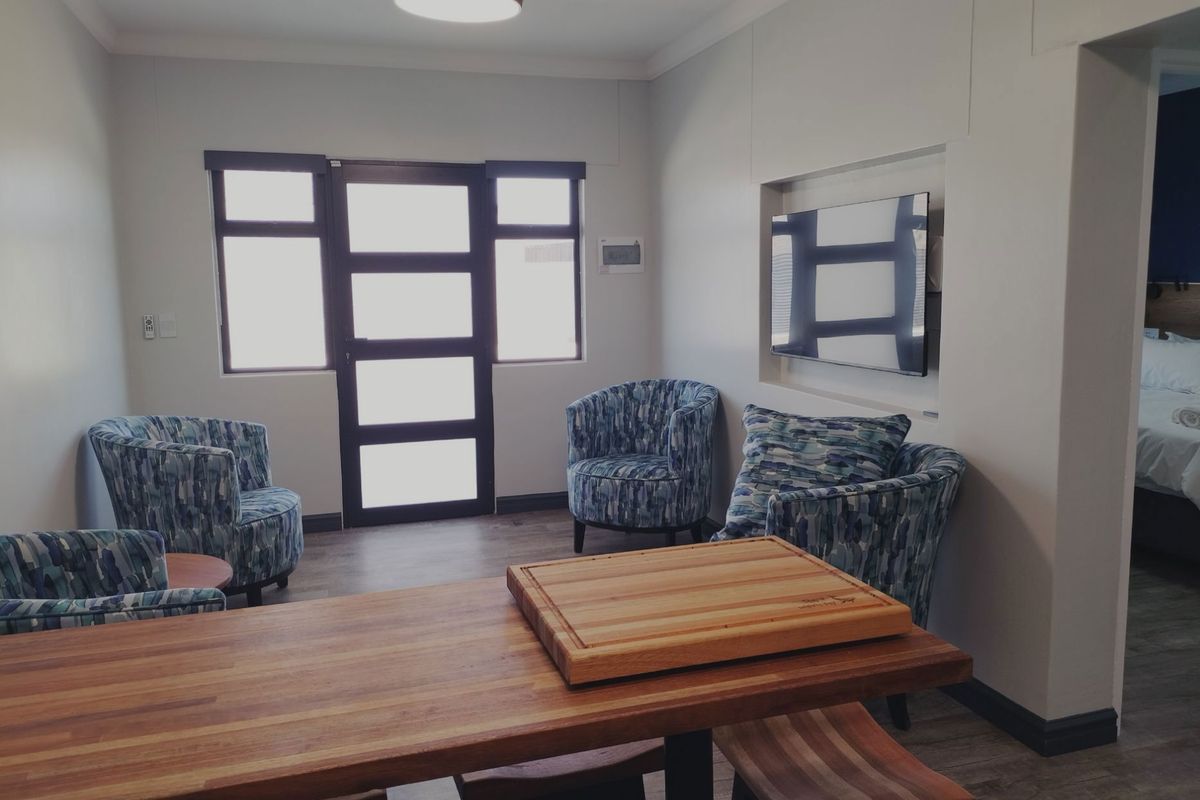A well-maintained living area featuring laminate flooring, a recessed wall niche for media, and a modern glass-paneled door providing natural light.