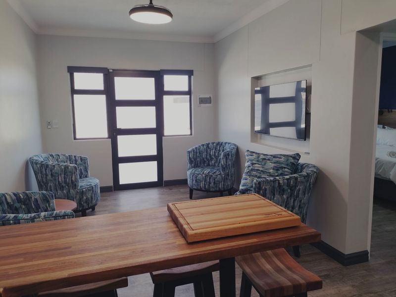 A well-maintained living area featuring laminate flooring, a recessed wall niche for media, and a modern glass-paneled door providing natural light.