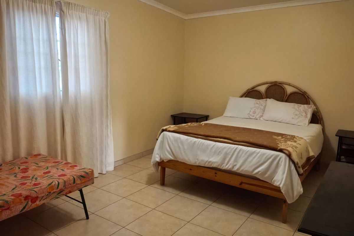 A functional bedroom featuring tiled flooring and neutral wall finishes, providing a simple and practical living space.