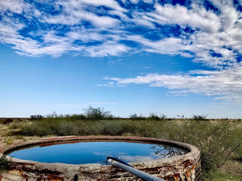 A circular corrugated metal water reservoir located on the farm property, showing signs of age and weathering.
