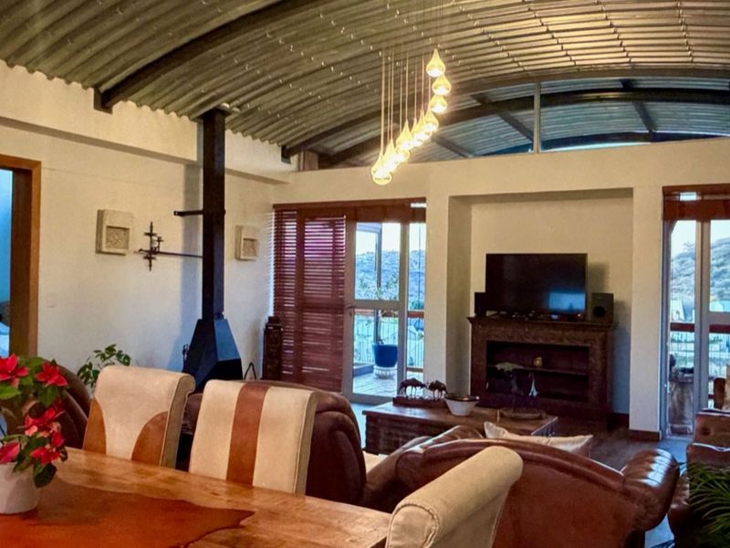 Spacious open-plan living area featuring a unique vaulted corrugated metal ceiling, a modern freestanding fireplace, and large sliding doors leading to an outdoor space.