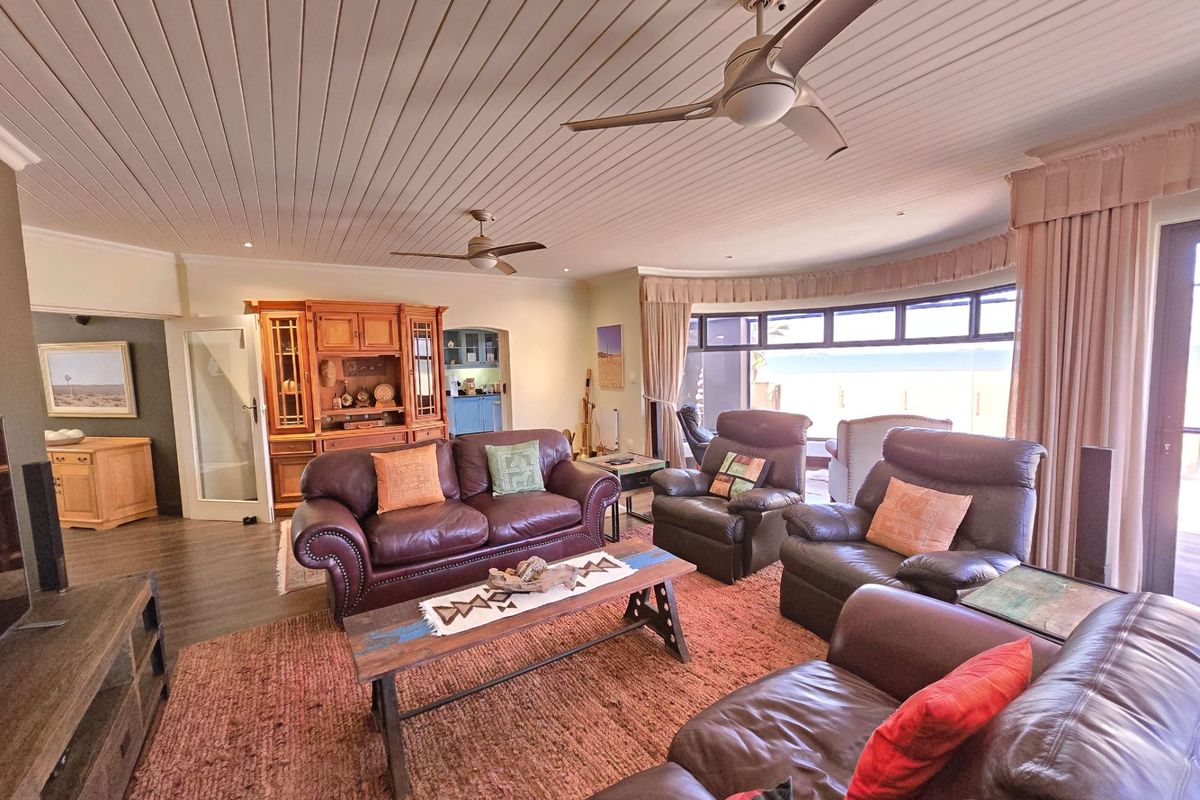 Spacious living room featuring a tongue and groove ceiling, dual ceiling fans, built-in cabinetry, and a large bay window with access to the patio.