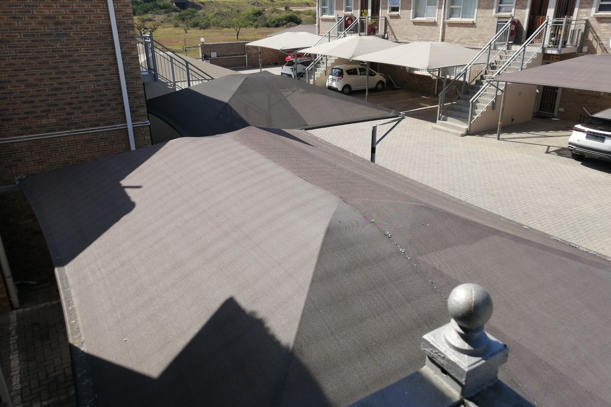 Elevated view of the complex parking area featuring multiple shade cloth carports and paved driveway access to the residential units.