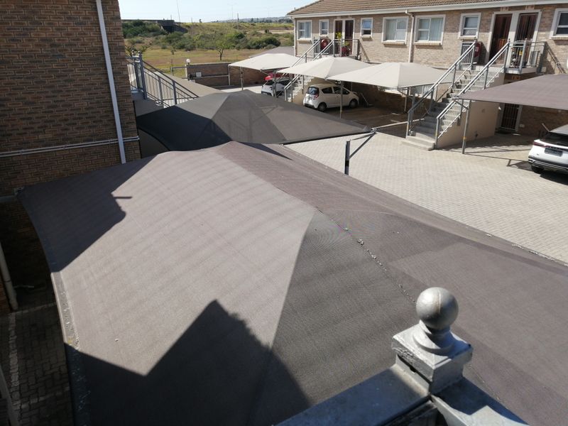 Elevated view of the complex parking area featuring multiple shade cloth carports and paved driveway access to the residential units.