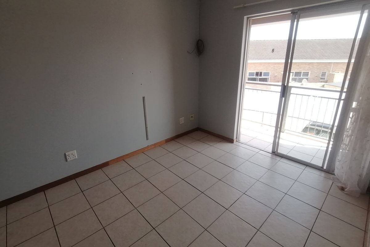 An empty bedroom featuring tiled flooring and a sliding glass door providing access to a balcony.