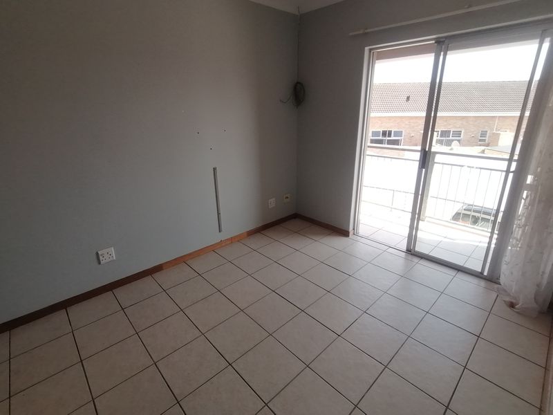 An empty bedroom featuring tiled flooring and a sliding glass door providing access to a balcony.
