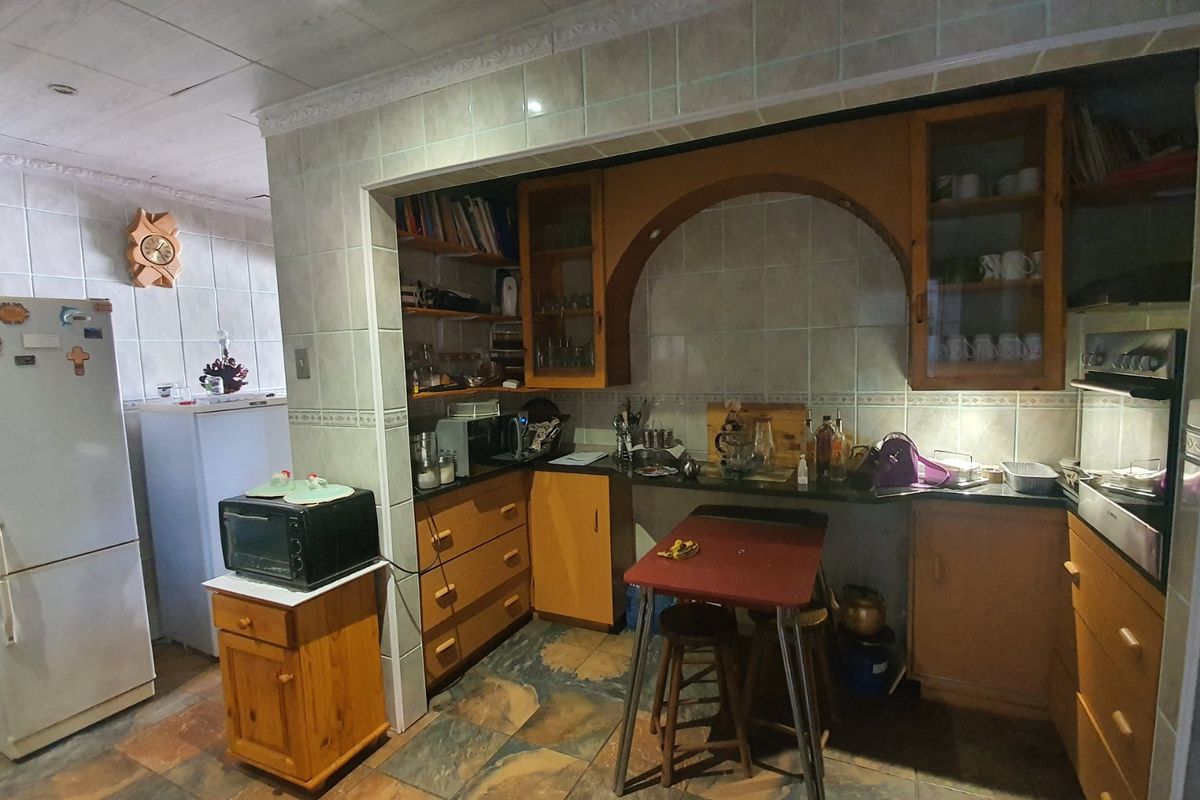 A dated kitchen featuring tiled walls, built-in wooden cabinetry, stone countertops, and an integrated oven, offering potential for a modern renovation.