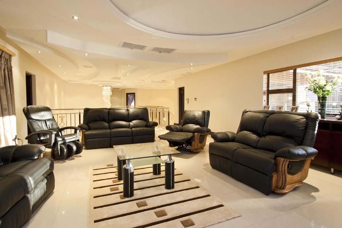 Spacious living room featuring a unique recessed ceiling design with integrated downlighting and polished tile flooring.