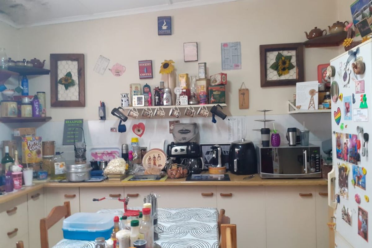 A functional kitchen featuring laminate countertops, built-in cabinetry, and a tiled splashback, currently showing signs of ceiling water damage.
