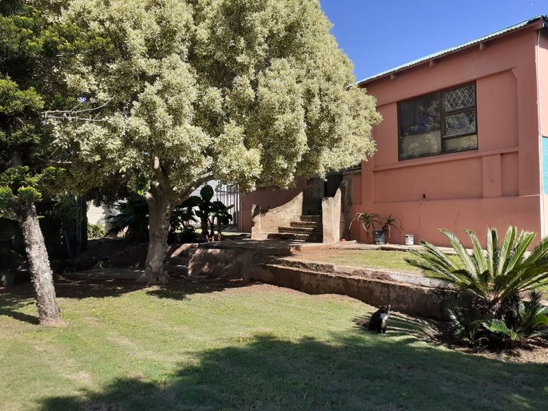 Rear garden area featuring a stone retaining wall, stone staircase, and mature landscaping adjacent to the main house structure.