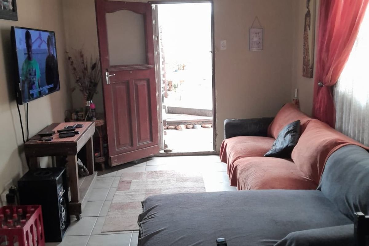 A functional living room featuring tiled flooring and direct access to the exterior through a timber entrance door.