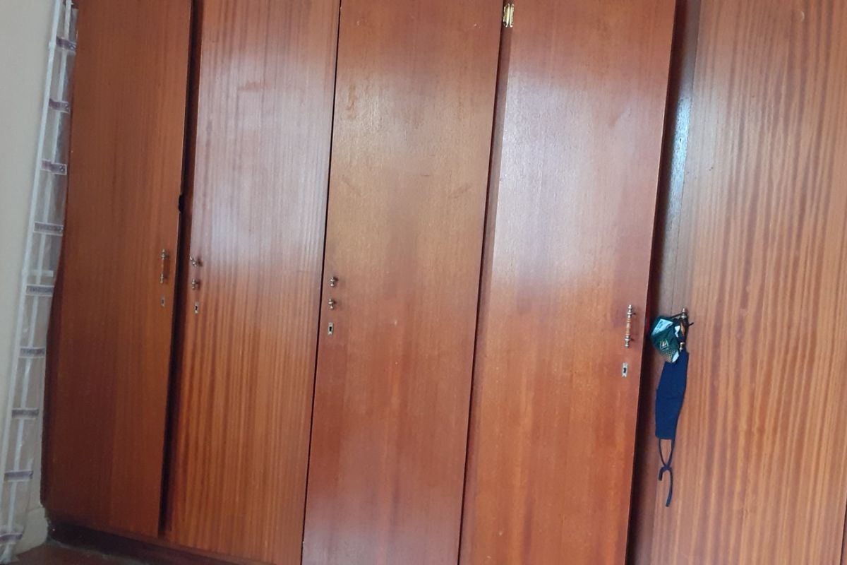 A bedroom featuring a large, dated built-in wooden wardrobe with multiple doors.