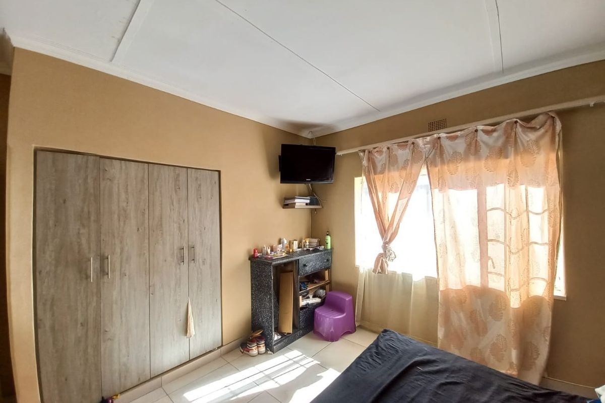 A bedroom featuring built-in wooden cabinetry, tiled flooring, and a window with curtain treatments.