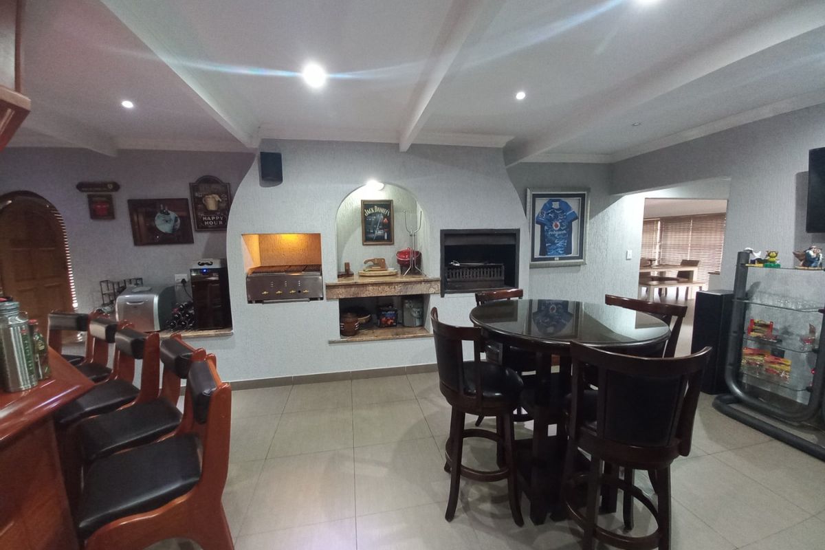 Spacious entertainment area featuring a built-in braai, tiled flooring, recessed lighting, and a bar counter, ideal for hosting guests.