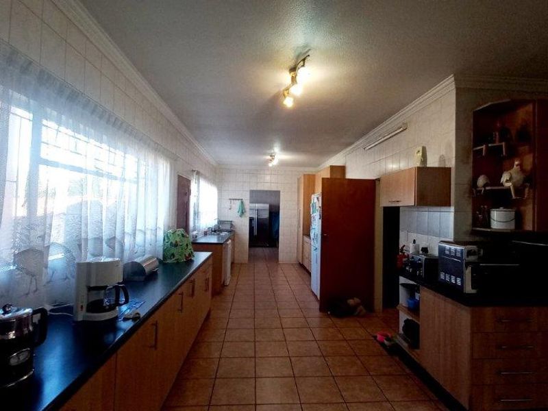 Spacious kitchen featuring extensive built-in cabinetry, tiled flooring, and a functional layout with ample counter space and integrated storage solutions.