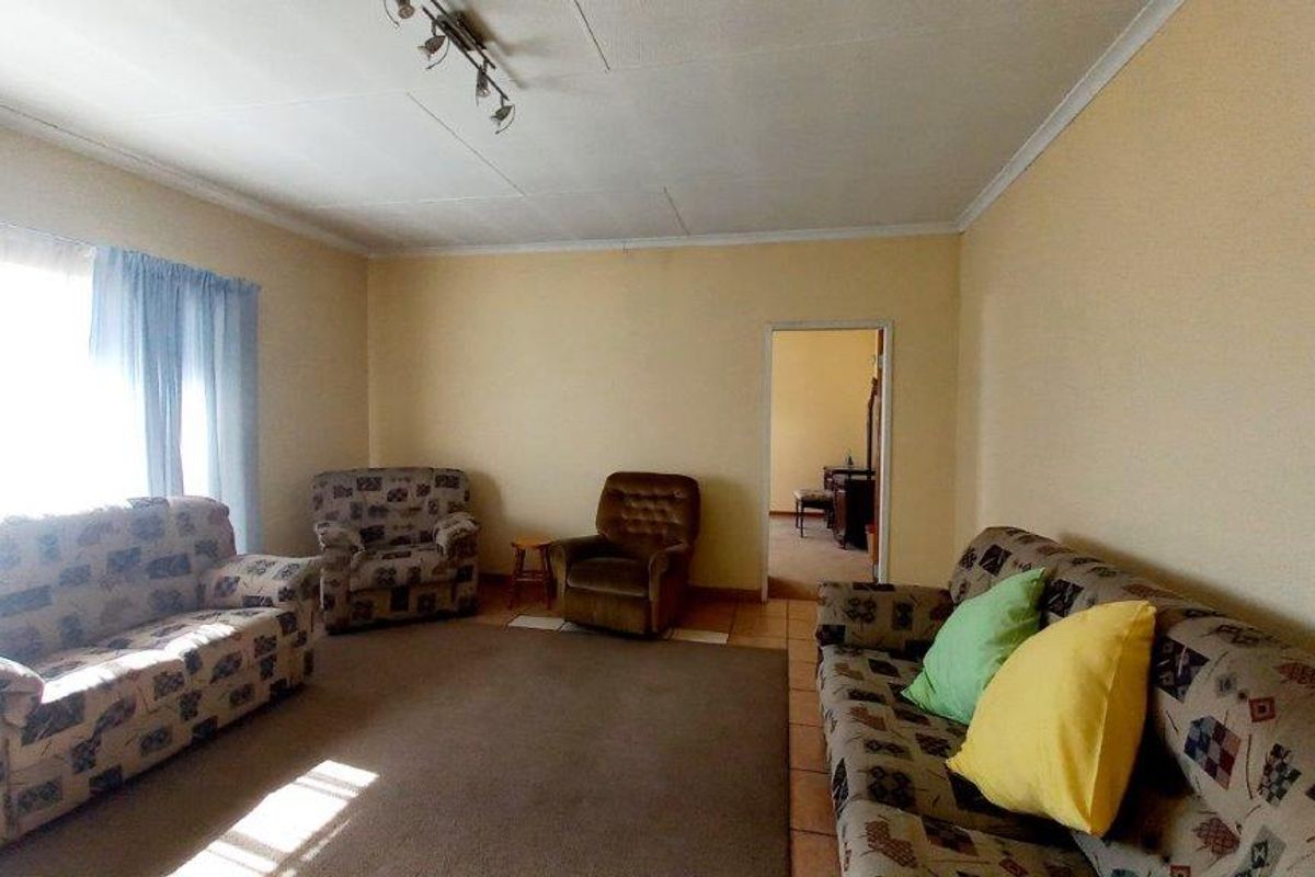 A spacious living room featuring tiled flooring and coved ceilings, offering a functional layout with natural light from the window.