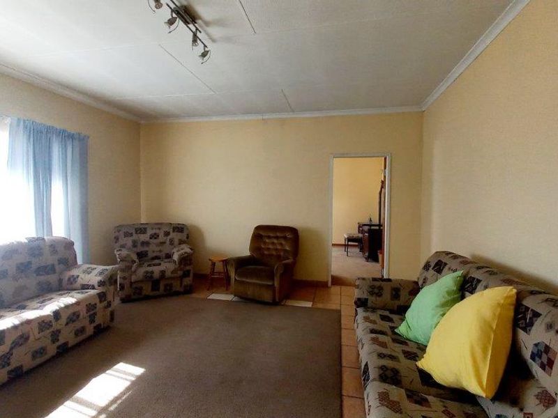A spacious living room featuring tiled flooring and coved ceilings, offering a functional layout with natural light from the window.