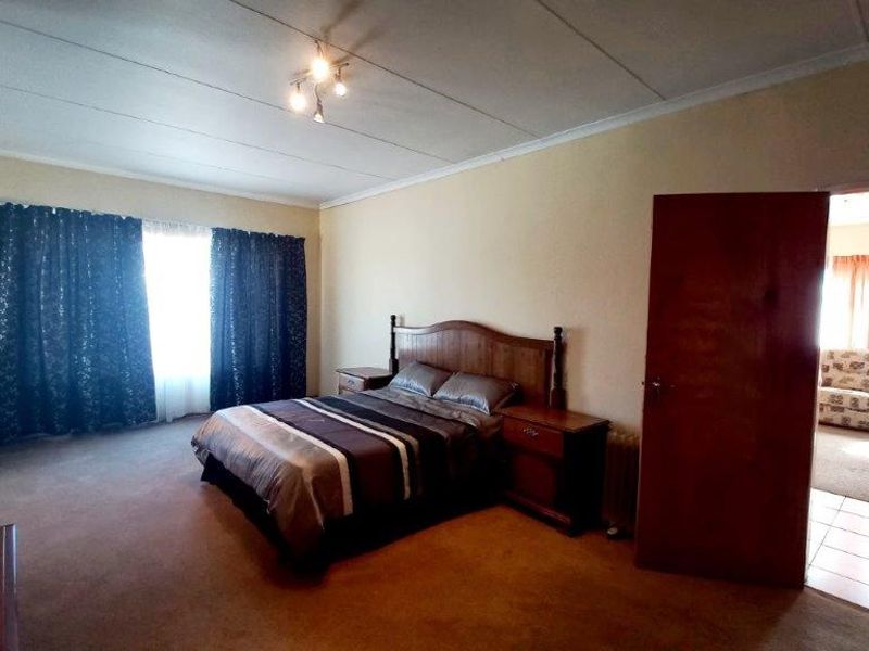 Spacious bedroom featuring carpeted flooring and direct access to an adjoining living area.