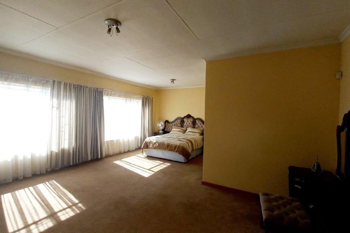 Spacious bedroom featuring large windows, carpeted flooring, and neutral wall tones, offering a blank canvas for potential interior updates.