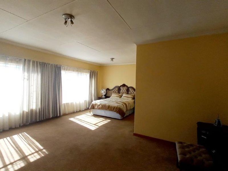 Spacious bedroom featuring large windows, carpeted flooring, and neutral wall tones, offering a blank canvas for potential interior updates.