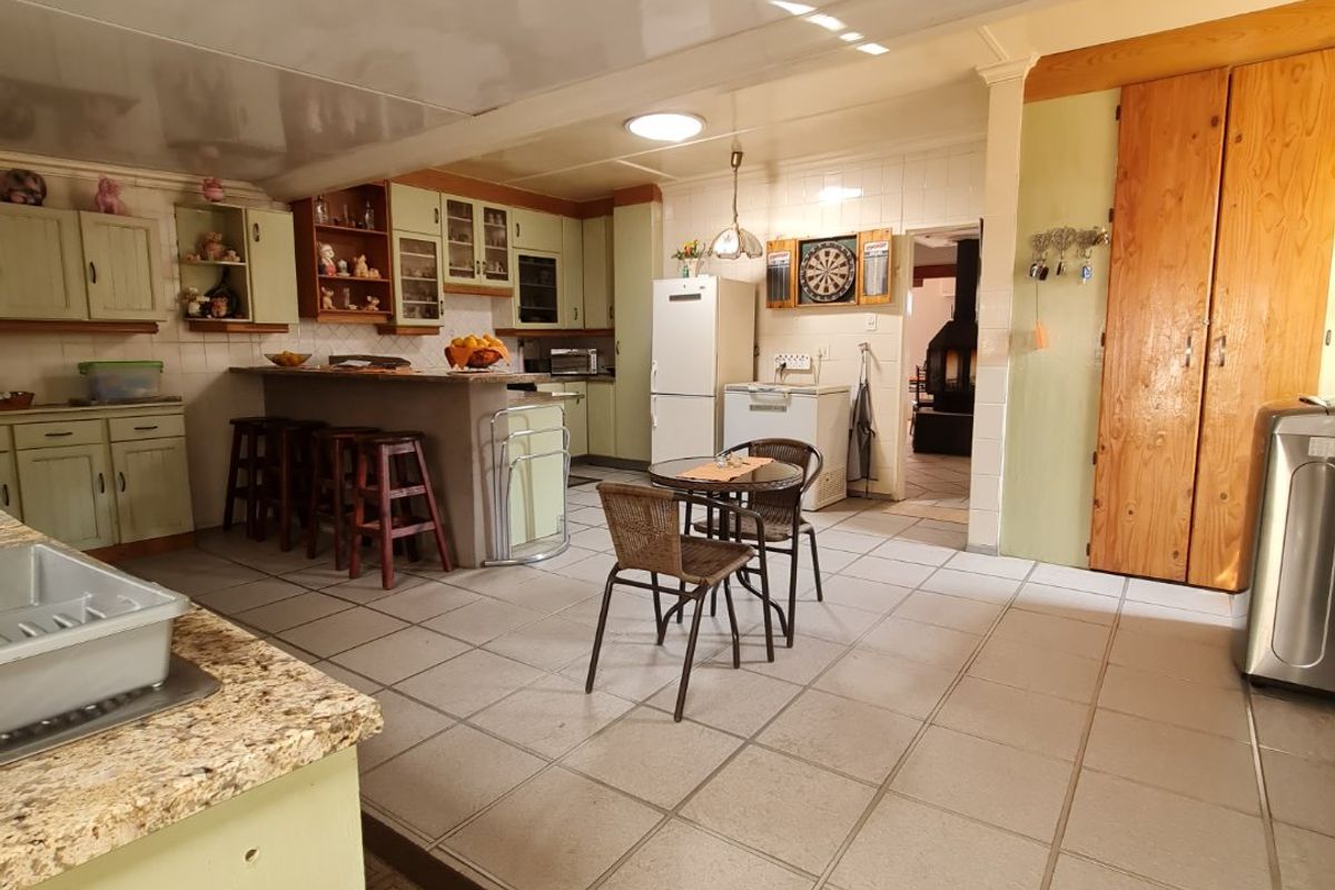 Spacious kitchen featuring a breakfast bar, tiled flooring, and ample built-in cabinetry, offering a functional layout with direct access to adjacent living areas.
