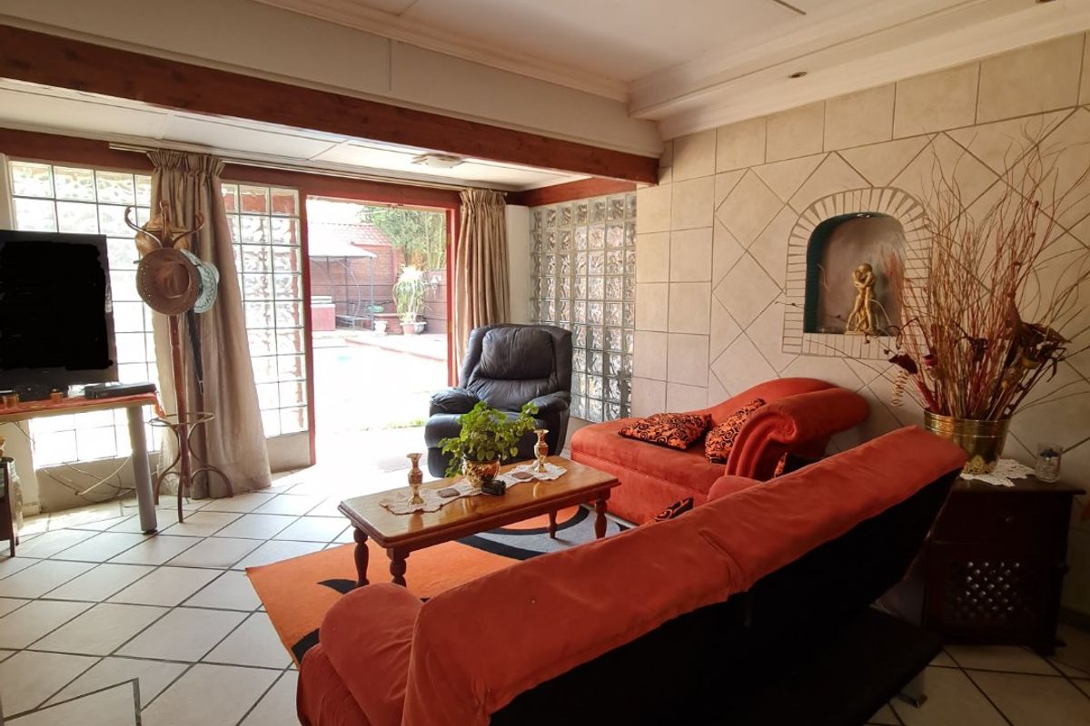 Spacious living room featuring tiled flooring, a built-in wall niche, and glass block accents, with direct access to the outdoor patio area.