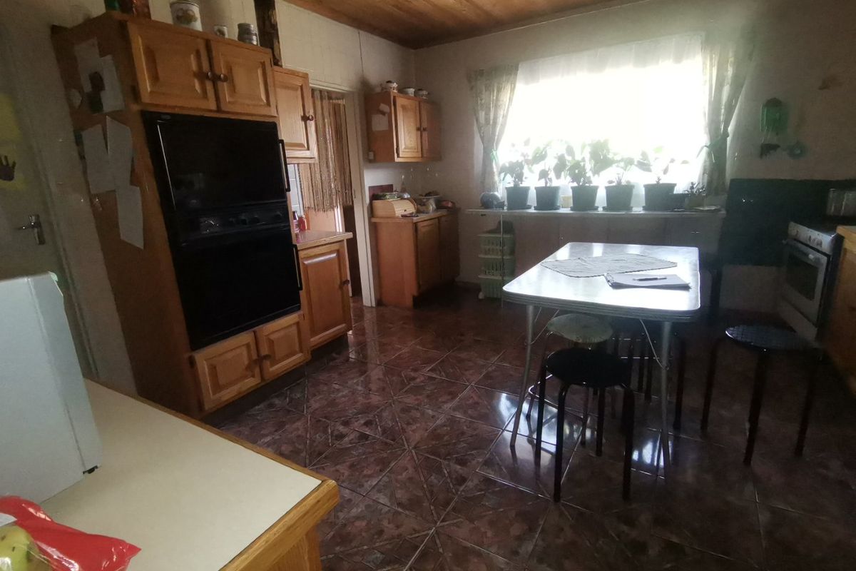 A dated kitchen featuring wooden cabinetry, a built-in oven, and tiled flooring, offering a functional layout with potential for modernization.