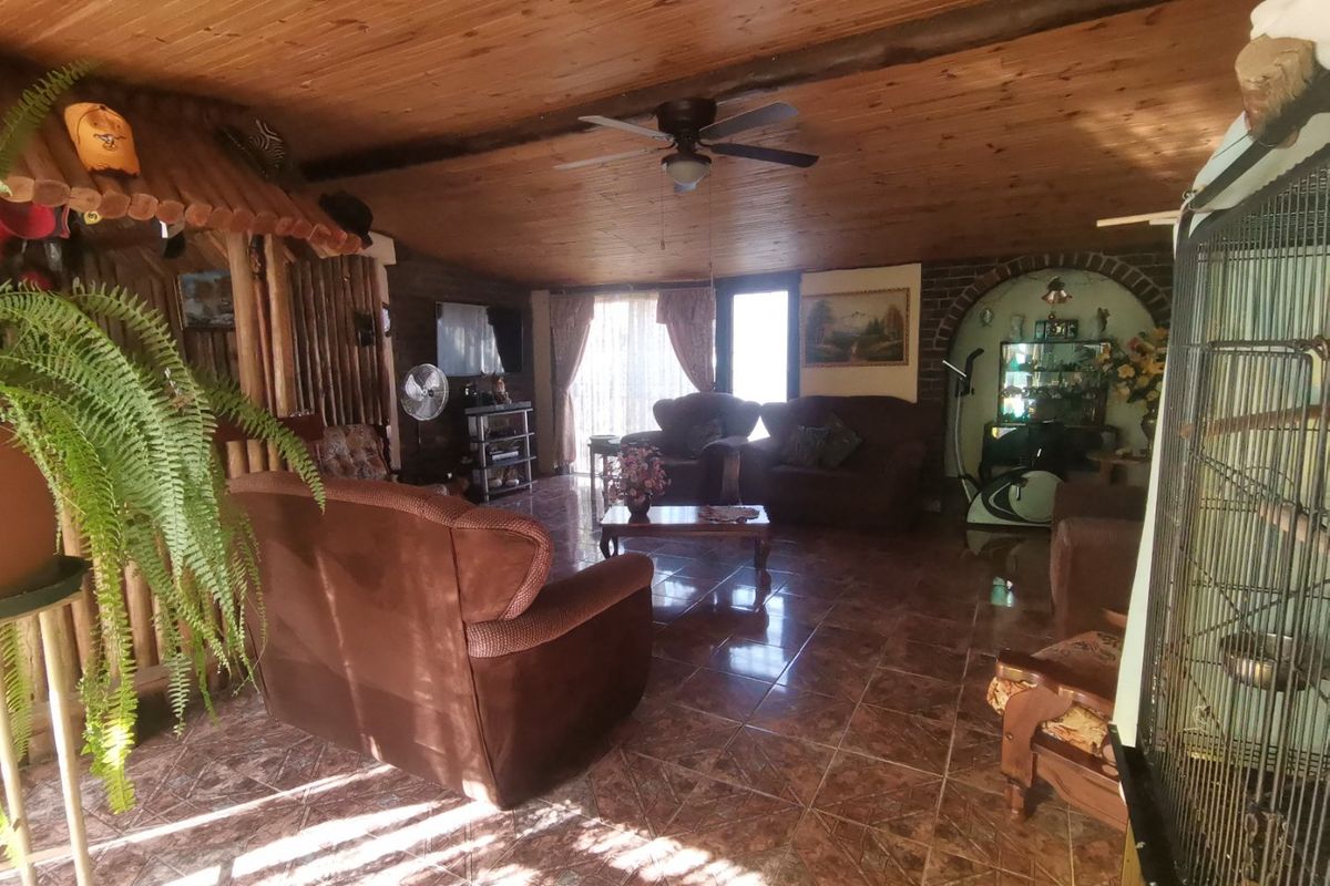 Spacious living room featuring a rustic wood-paneled ceiling, tiled flooring, and a built-in arched display alcove with brick detailing.