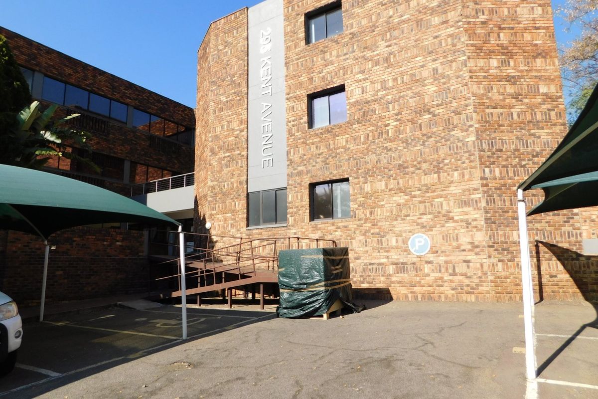 Front exterior view of the office building at 298 Kent Avenue, featuring brick facade, parking area with shade cloth carports, and a wheelchair access ramp.