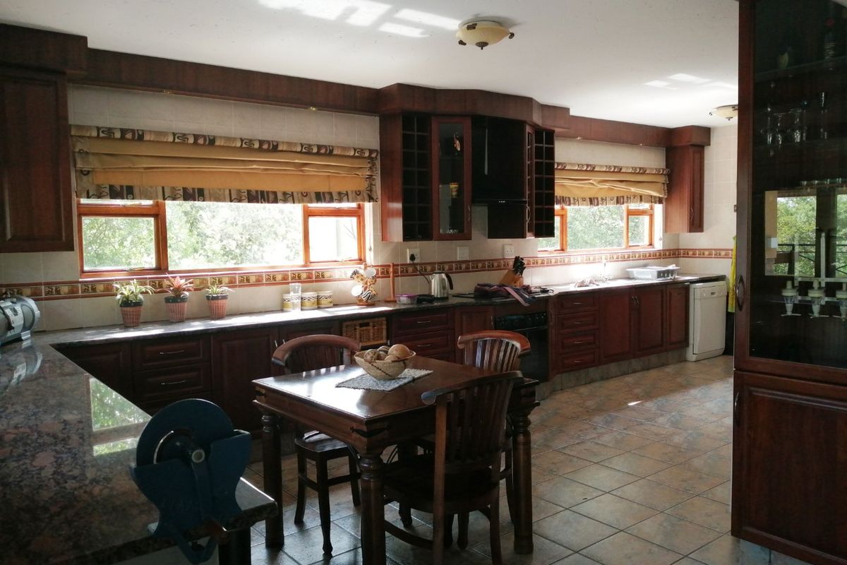 Spacious kitchen featuring dark wood cabinetry, granite countertops, tiled flooring, and integrated storage solutions with ample natural light.