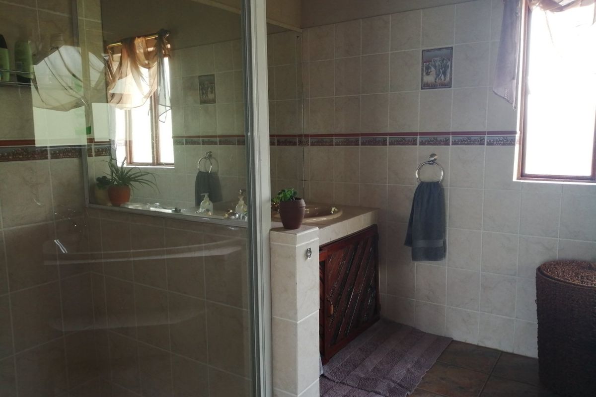 A functional bathroom featuring a glass-enclosed shower, tiled walls, and a built-in vanity unit with a basin.