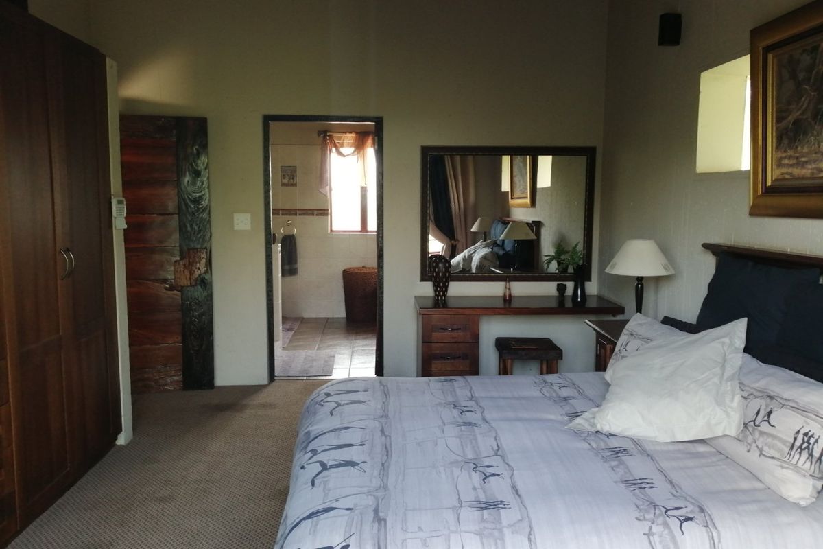 A spacious bedroom featuring built-in wooden cabinetry and an en-suite bathroom entrance, with neutral wall finishes and carpeted flooring.