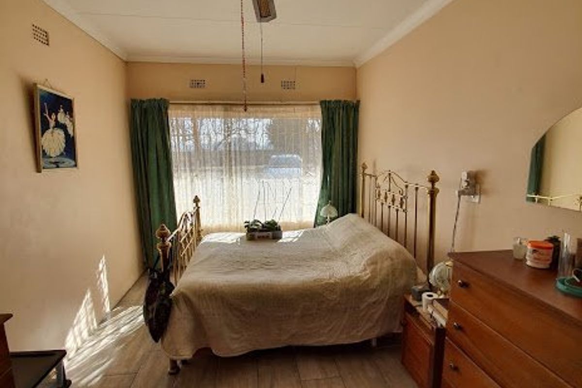 A bedroom featuring wood-look tiled flooring, a ceiling fan, and large windows with natural light.