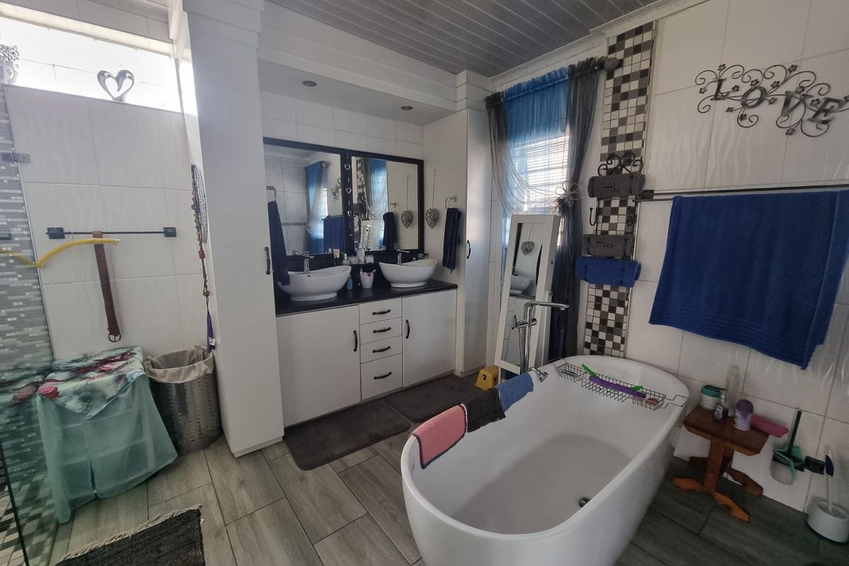 A spacious bathroom featuring a freestanding bathtub, a double vanity with vessel sinks, and a separate glass-enclosed shower area.