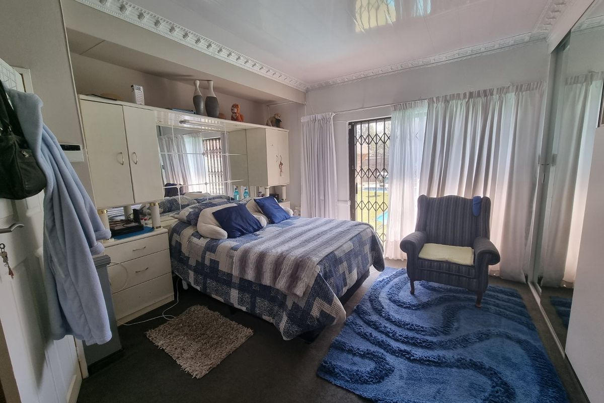 A bedroom featuring built-in cabinetry with integrated mirror, decorative ceiling cornices, and a sliding door providing access to the outdoor area.