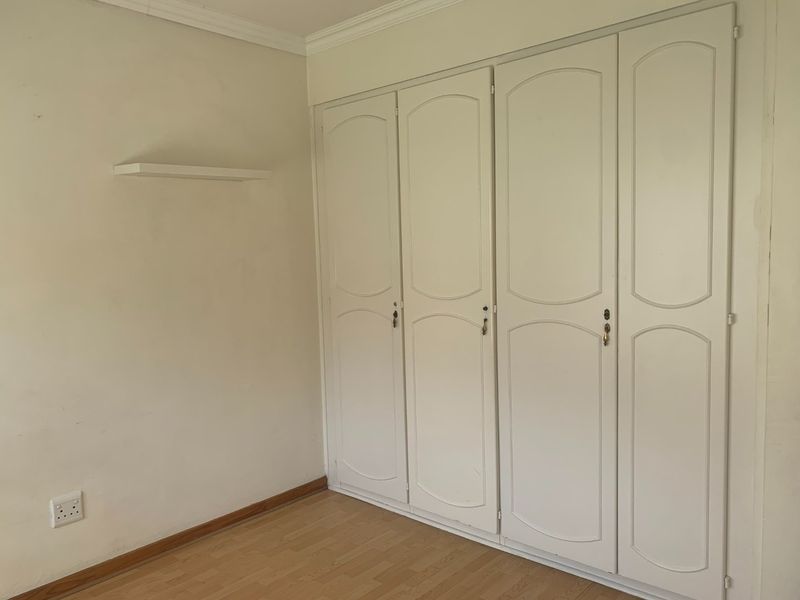 A bedroom featuring built-in white cabinetry with classic panel detailing and light wood-look flooring.