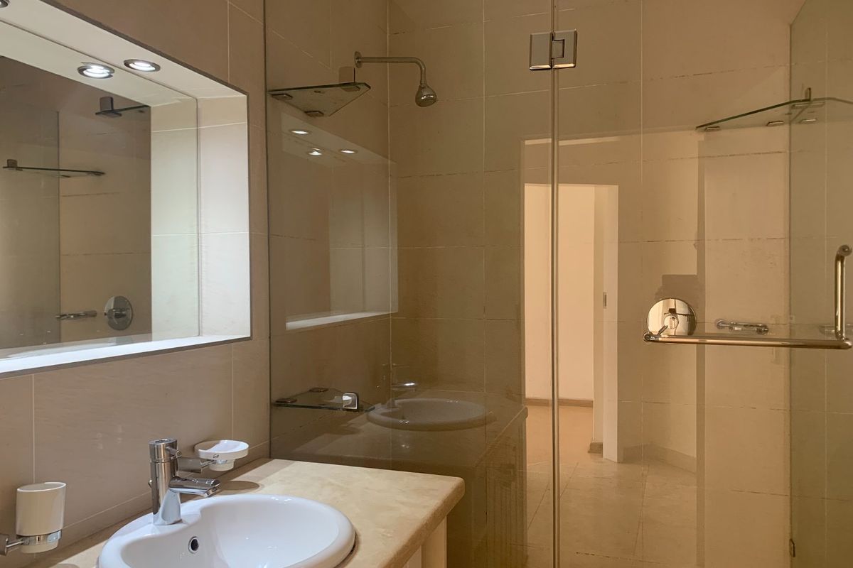 Modern bathroom featuring a glass-enclosed shower, stone-topped vanity with integrated basin, and a large wall-mounted mirror with recessed lighting.