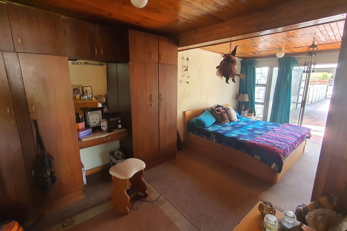 Spacious bedroom featuring extensive built-in wooden cabinetry, a vanity area, and direct access to an outdoor patio through sliding glass doors.