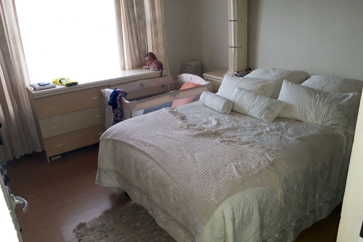 A bedroom featuring built-in cabinetry and laminate flooring, providing a functional space with natural light from the window.