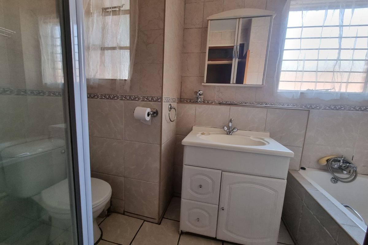 A functional bathroom featuring a built-in vanity, a separate shower enclosure, and a bathtub with tiled wall finishes.