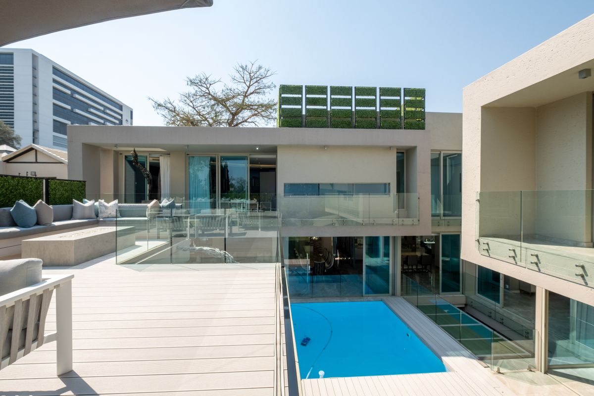 Modern architectural exterior featuring a multi-level deck, glass balustrades, and a swimming pool, showcasing contemporary design and seamless indoor-outdoor flow.