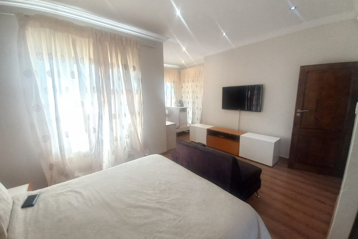 A bedroom featuring laminate flooring, recessed ceiling lighting, and a wall-mounted television point.