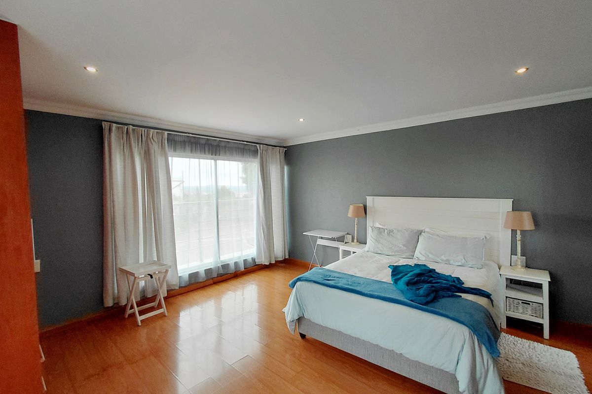 Spacious bedroom featuring polished timber flooring, recessed downlighting, and large sliding glass doors providing natural light.