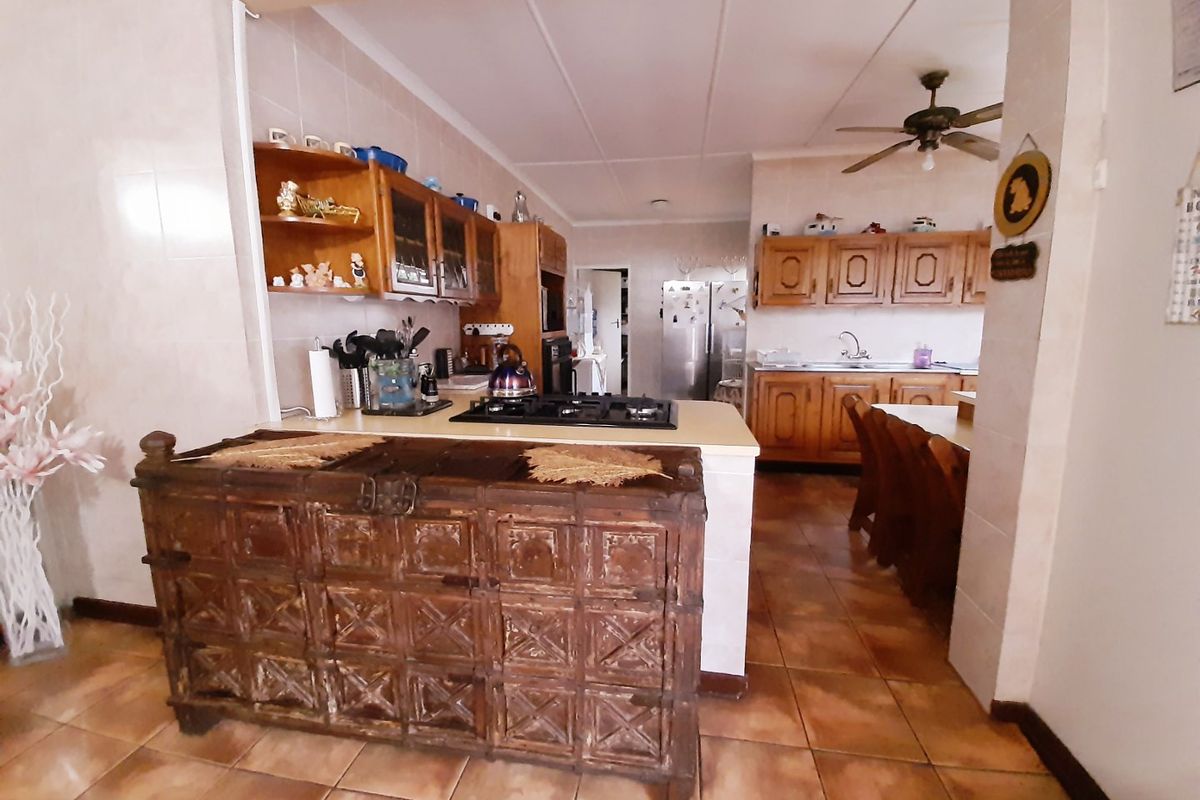 A functional kitchen featuring wooden cabinetry, a built-in gas hob, and tiled flooring, offering a traditional layout with ample storage space.